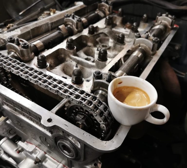 Eine Kaffeetasse steht auf einem Motorblock mit offenen Bauteilen.
